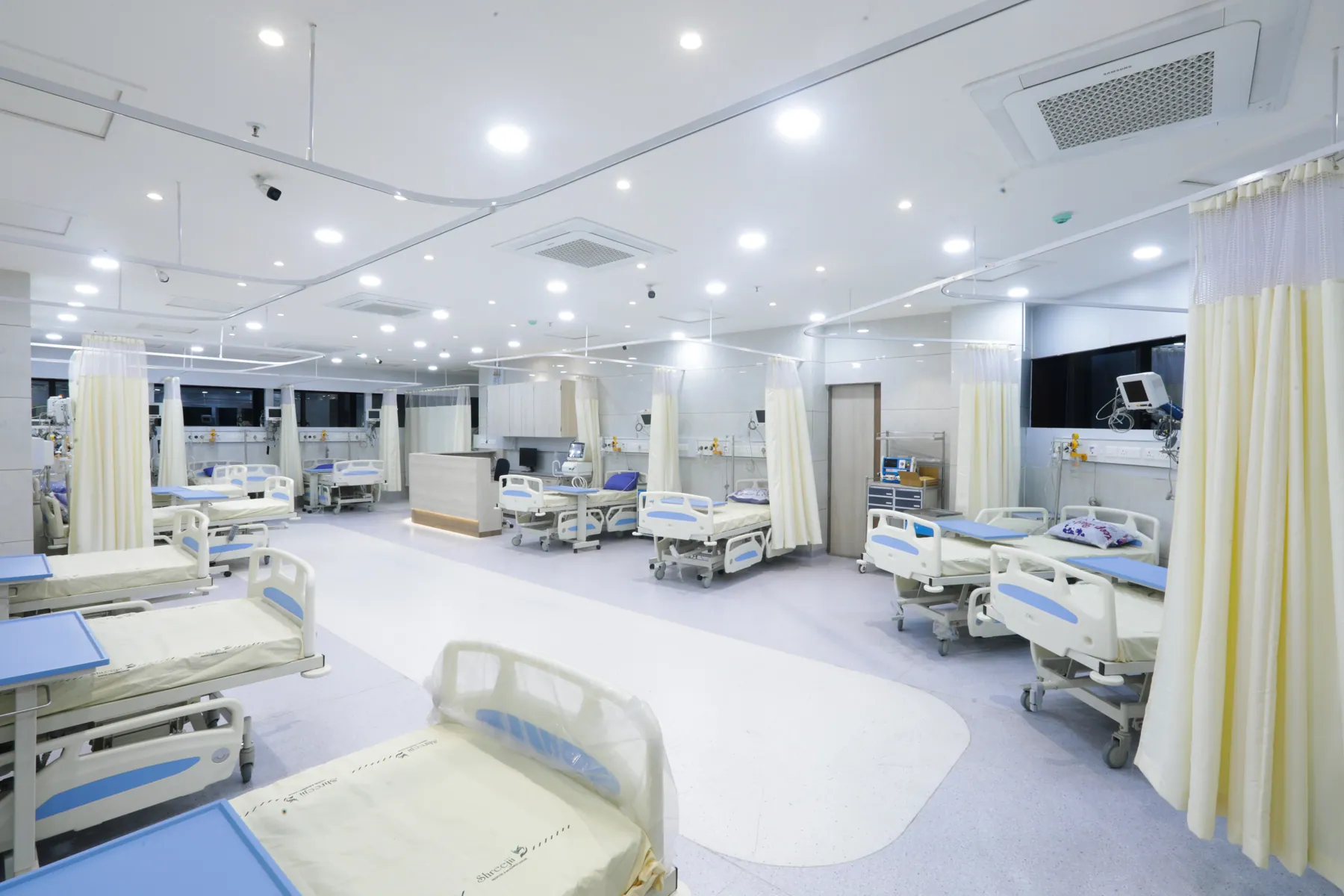 Wide view of a multi-bed ward with curtained bays
